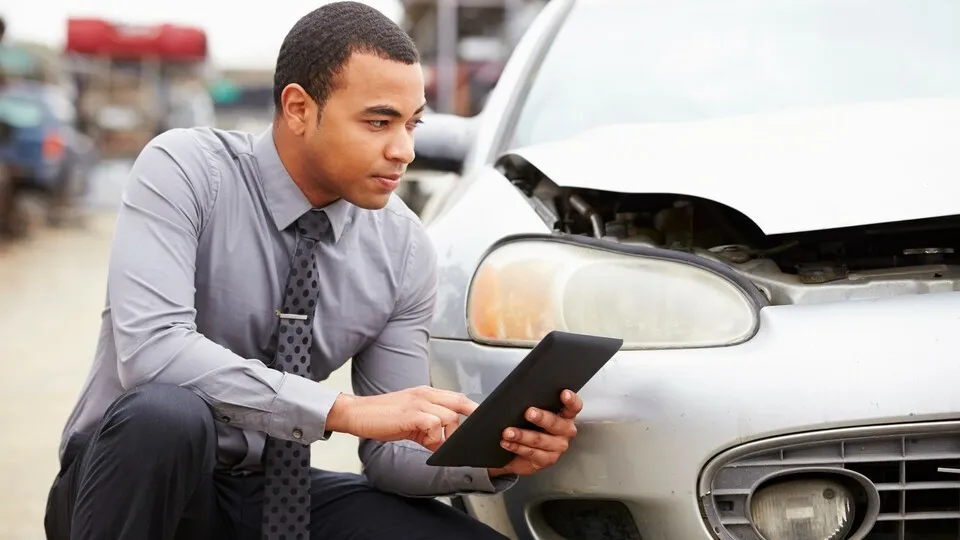 04 Nov 2013 --- Loss Adjuster Using Digital Tablet In Car Wreck Inspection --- Image by © Monkey Business Images/Corbis